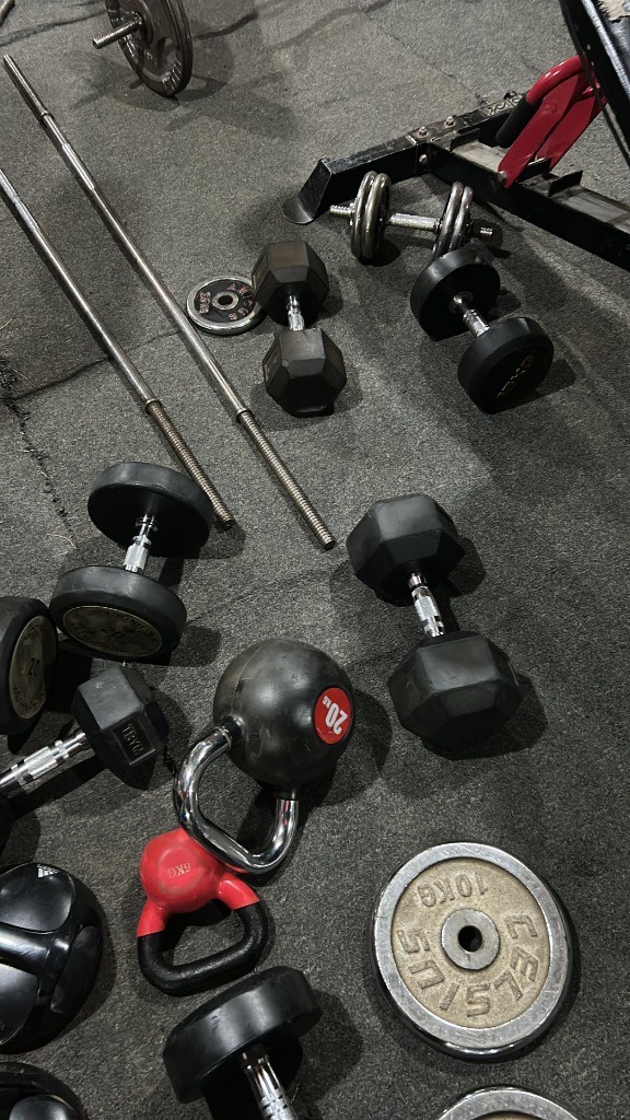 Dumbbells, kettlebells, barbell bars, and weight plates on G:Lite Hub gym floor