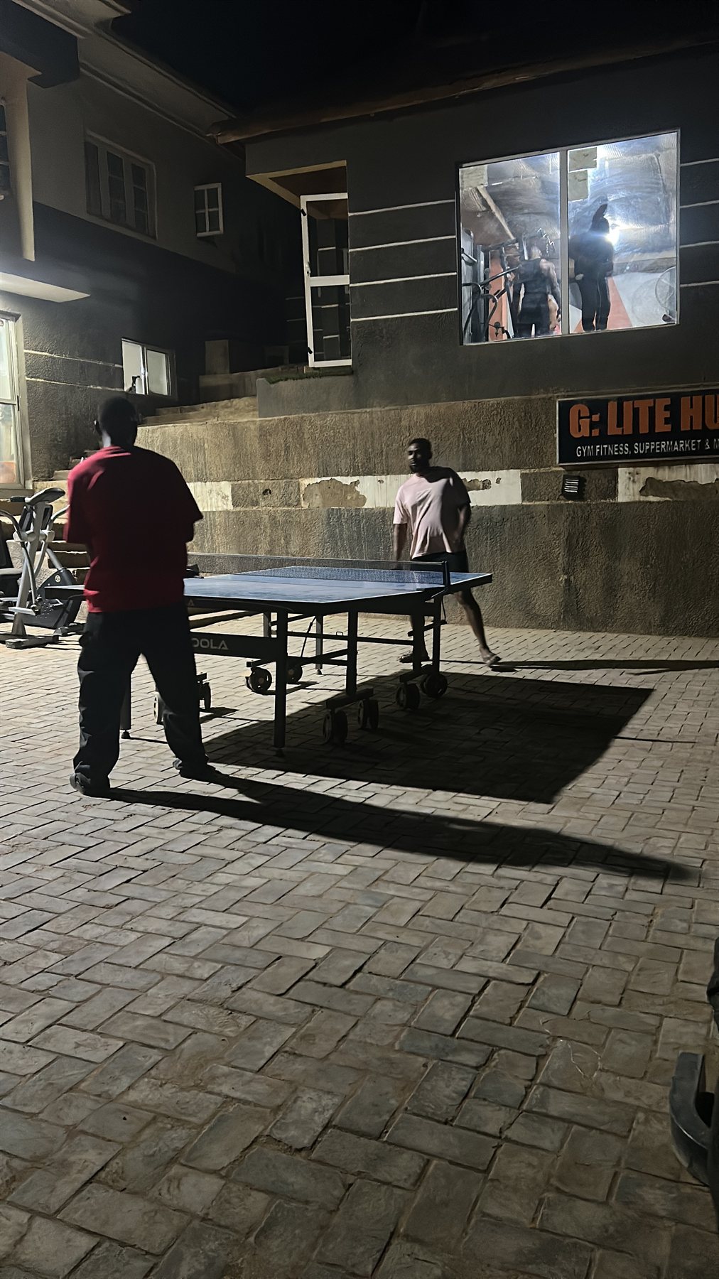 Table tennis under evening lights with G:LITE HUB sign